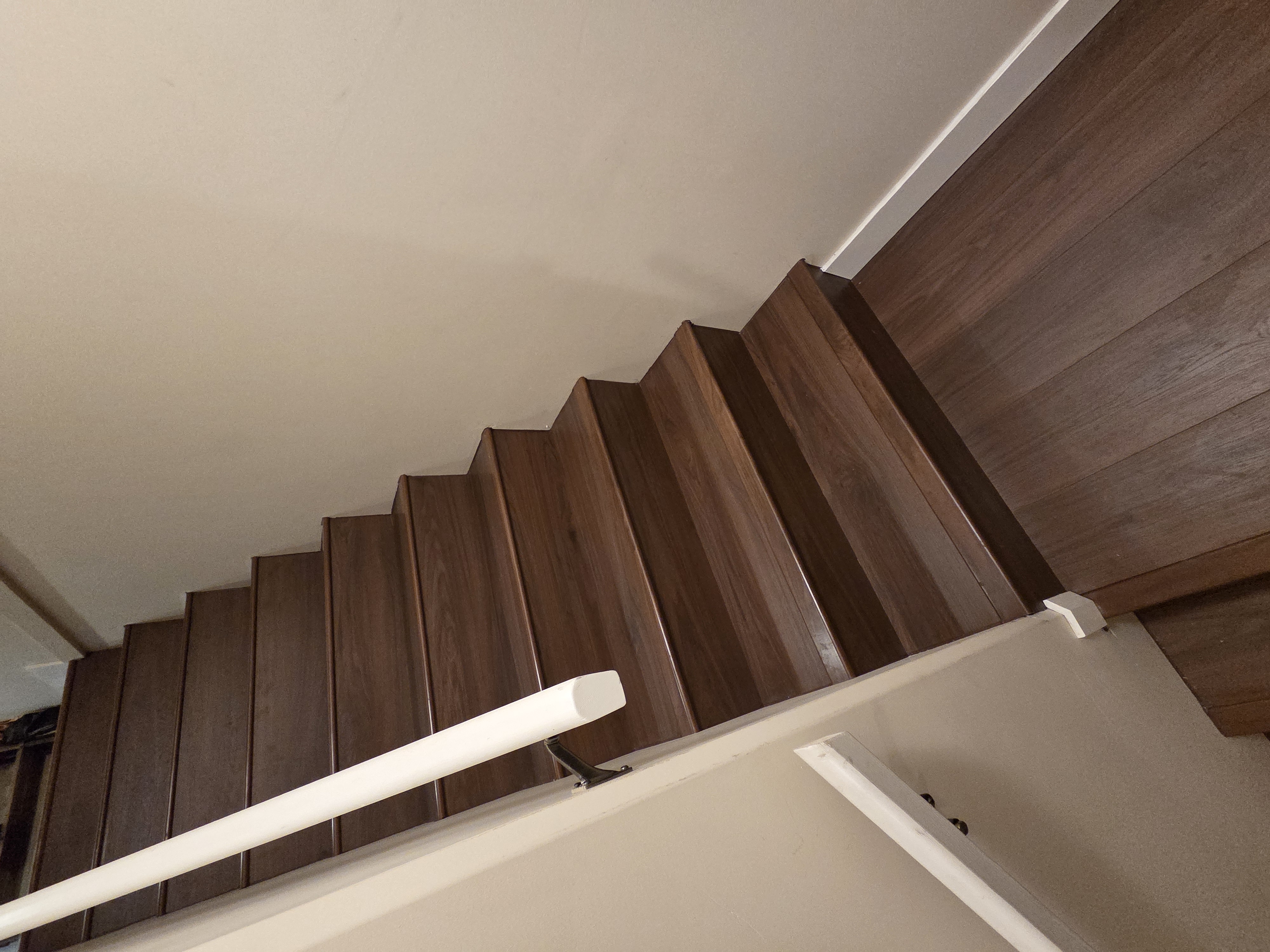 Finished staircase with dark hardwood treads and white painted handrail